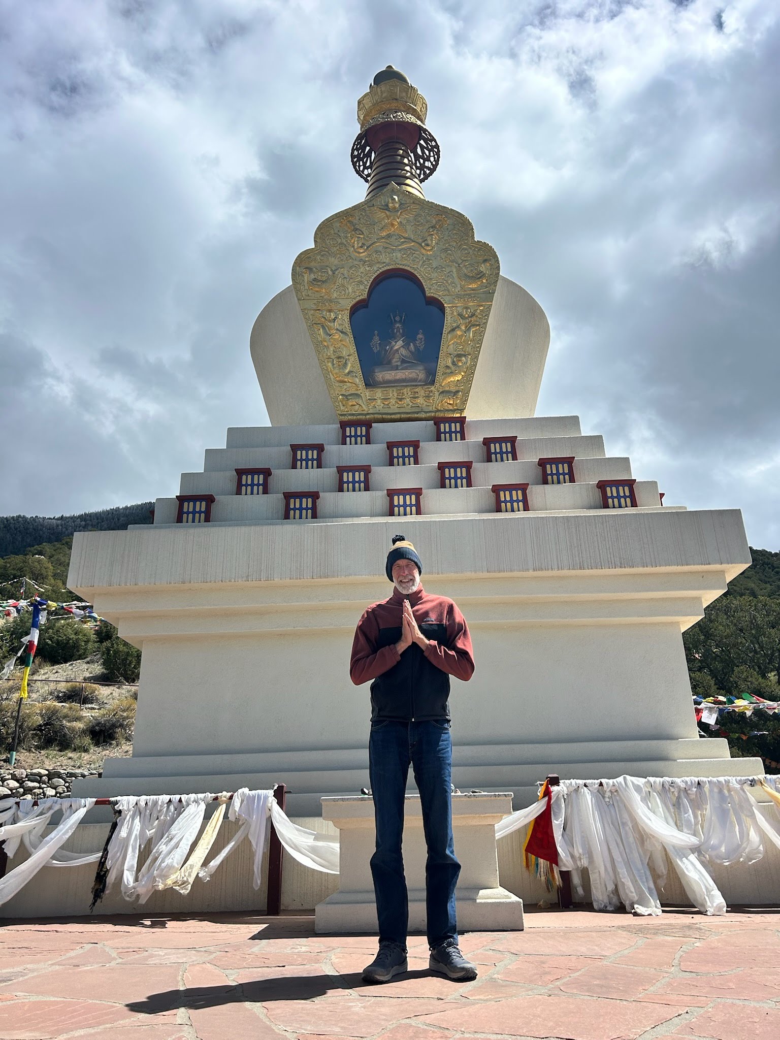 Author M. C. Tyson standing in front of a white Buddhist stupa with a golden top
